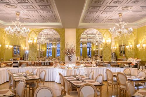 una sala da pranzo con tavoli, sedie e lampadari a braccio di Hotel Principe a Venezia