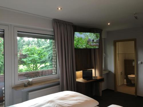 a bedroom with a bed and a window with a television at Landhaus Hotel Göke in Hövelhof