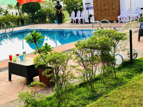 a swimming pool with a table and chairs next to it at VITS Kamats Resort, Silvassa in Silvassa