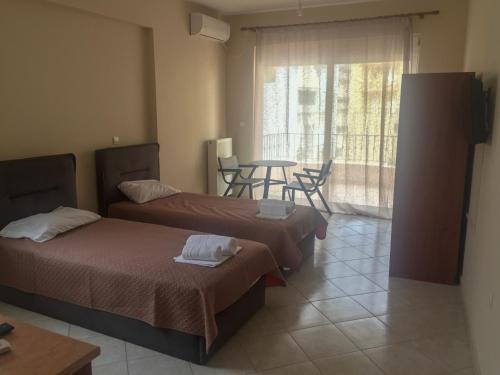 a room with two beds and a table with chairs at Theros Apartment Preveza in Preveza