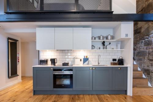 a kitchen with gray cabinets and white appliances at Linton Collection - Blackfriars Lofts in Edinburgh