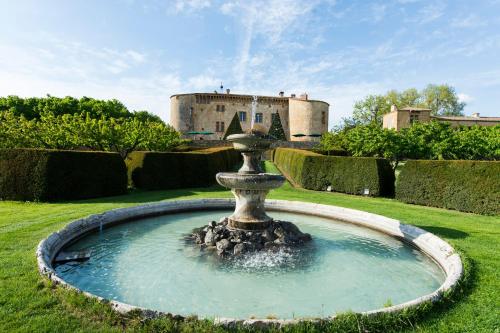 a fountain in a yard with a castle in the background at Château de Bagnols in Bagnols