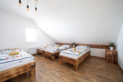 a room with three beds and wooden floors at Penzion Šarlota & Vinařství Vítek Josef in Mutěnice
