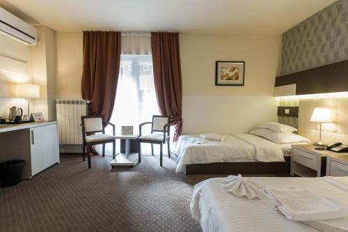a hotel room with two beds and a table and chairs at Bacolux Afrodita, Herculane in Băile Herculane