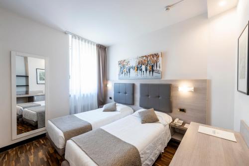 a hotel room with two beds and a table at Hotel Asnigo in Cernobbio
