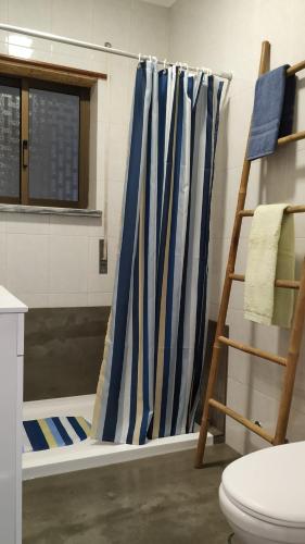 baño con cortinas de ducha azules y blancas y escalera en Sun House - Baleal, en Ferrel