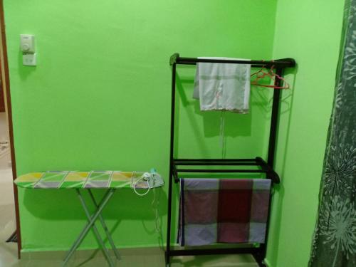 a green room with a towel rack and a table at HR Iman Homestay in Dungun