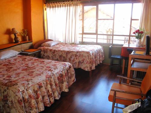 a hotel room with two beds and a window at Casa De Mama Cusco - The Treehouse in Cusco