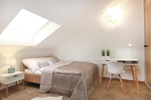 a bedroom with a bed and a desk and a skylight at Sky-apartment in Povljana