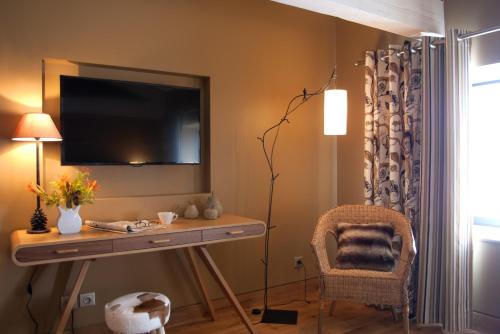 a living room with a desk and a television on a wall at André et Viviane Chatelard - Chambres d'hôtes in Saint-Bonnet-le-Froid