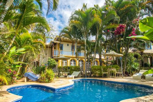 een zwembad voor een huis met palmbomen bij Arraial Velho Pousada Tematica in Tiradentes