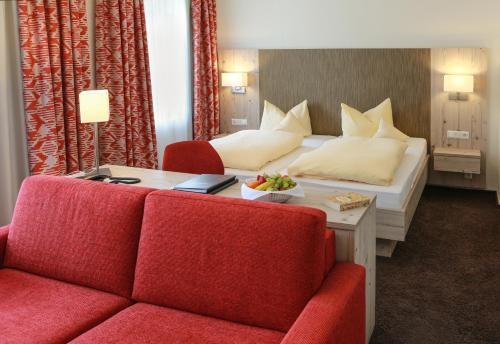 a hotel room with a bed and a red couch at Rüters Parkhotel in Willingen
