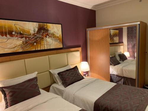 ein Hotelzimmer mit 2 Betten und einem Spiegel in der Unterkunft Altelal Apartment in Mekka