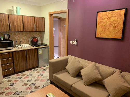 a living room with a couch and a kitchen at Altelal Apartment in Makkah