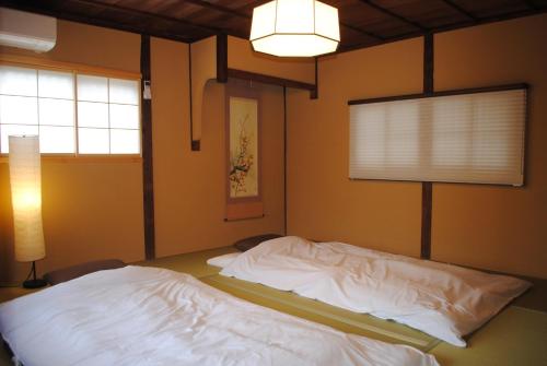 a bedroom with a white bed with a lamp and a window at NARAigoto EENA HOUSE in Nara
