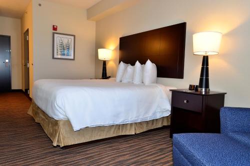 a hotel room with a large bed and a blue chair at Cobblestone Inn & Suites - Holstein in Holstein