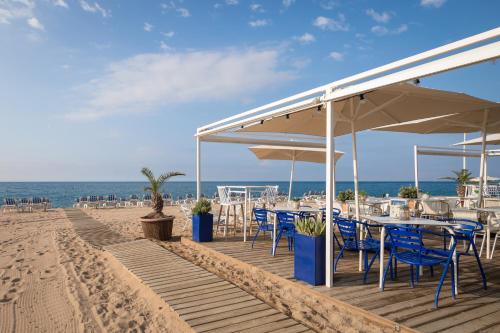 a restaurant on the beach with blue chairs and umbrellas at htop Olympic #htopEnjoy in Calella