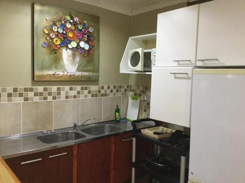 a kitchen with a sink and a painting on the wall at The Buddha Garden in Cape Town