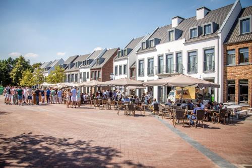 a group of people sitting at tables and umbrellas on a street at Dormio Resort Maastricht Apartments in Maastricht