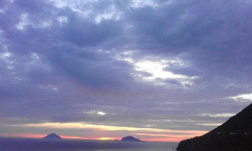 a cloudy sky over the ocean with mountains in the distance at Casa Katia in Lingua