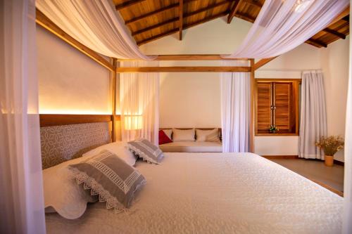 a bedroom with a large bed with white sheets at Pousada Recanto do Arraial in Arraial d'Ajuda