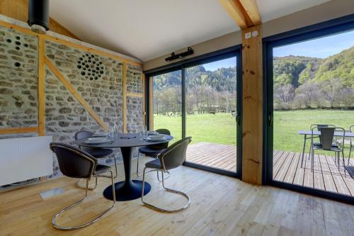 a dining room with a table and chairs and sliding glass doors at La Dormeuse du Val in Chambon-sur-Lac