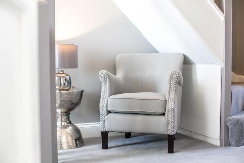 a white chair in a stair room with a lamp at The Alexander - Donnini Deluxe in Prestwick