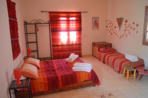 a bedroom with two beds and a table and a window at Casa Naima in Ida Ougourd
