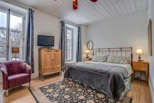 a bedroom with a bed and a tv and a chair at Manoir Sur le Cap in Quebec City