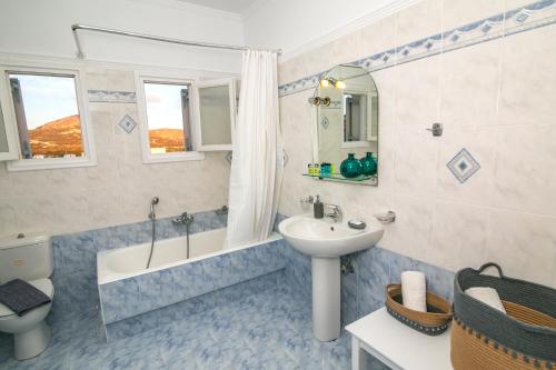 a bathroom with a sink and a tub and a toilet at Caldera Sunset Villa in Megalokhori