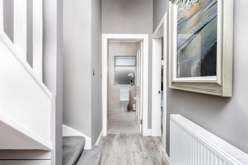 a hallway with a toilet and a painting on the wall at The Alexander - Donnini Deluxe in Prestwick