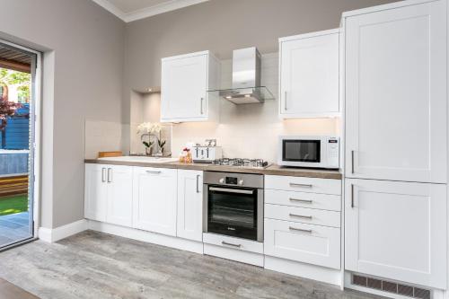 a white kitchen with white cabinets and appliances at The Alexander - Donnini Deluxe in Prestwick