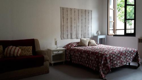 um quarto com uma cama, uma cadeira e uma janela em Location Saint Antonin em Saint-Antonin