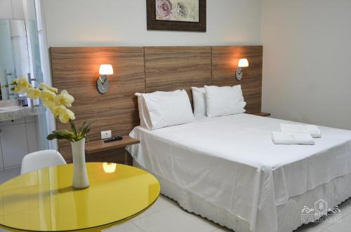 um quarto de hotel com uma cama e uma mesa amarela em Hotel das Torres em Guanambi