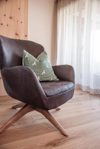 a brown chair with a green pillow in a room at Penthouse Chalet Pichlerhof in Brunico