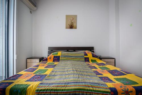 a bed with a colorful quilt on it in a room at Cozy One-bedroom Apartment in Night Breeze in Burgas