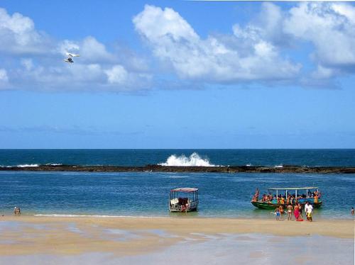 a group of people standing on a beach with two boats at Pousada Brisa e Mar in Praia do Frances