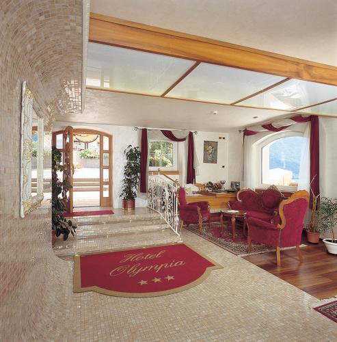 a living room with red chairs and a table at Hotel Olympia in Molveno