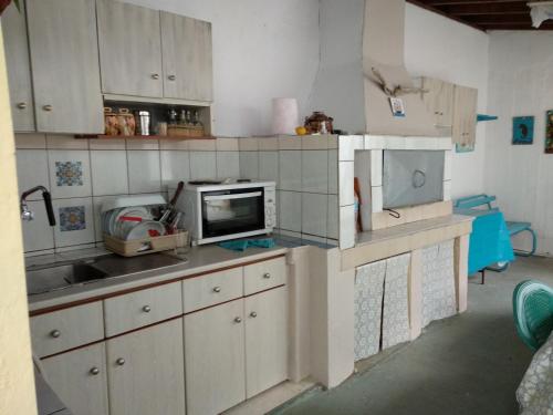 een keuken met witte kasten, een wastafel en een tv bij Villa Dallas in Vourvourou