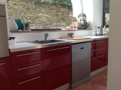 a kitchen with red cabinets and a sink and a window at Montalcino Loft in Montalcino