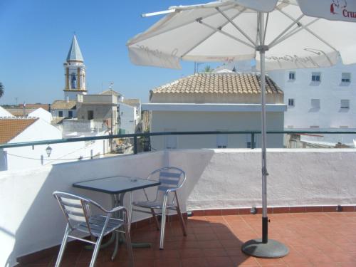 d'une table et de chaises sur un balcon avec un parasol dans l'établissement Hostal Muriel, à Aljaraque