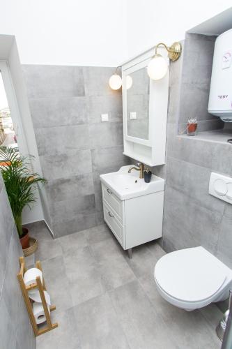 a bathroom with a white toilet and a sink at Apartments and Rooms Ille in Šibenik