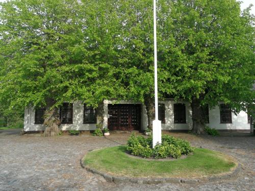 un poteau en face d'un bâtiment avec un arbre dans l'établissement Alter Erker, à Fehmarn
