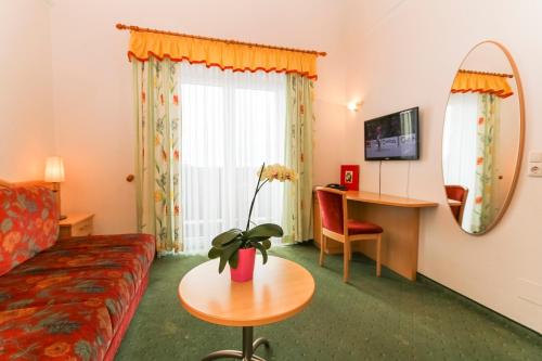 ein Hotelzimmer mit einem Sofa, einem Tisch und einem Spiegel in der Unterkunft Alpenhotel Tauernstüberl in Zell am See