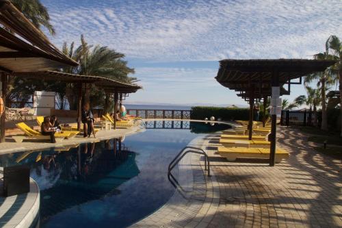 a pool at a resort with people sitting on chairs at Nesima Resort in Dahab