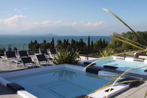 a swimming pool with chairs and the ocean in the background at Hotel Berta in Desenzano del Garda
