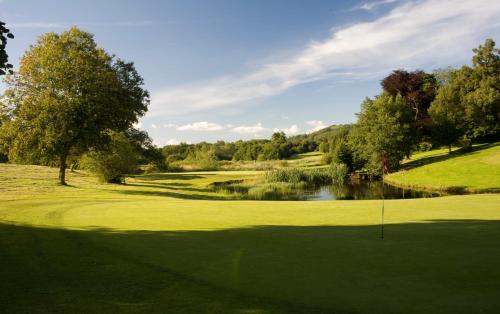 a golf course with a hole and a pond at Cally Palace Hotel & Golf Course in Gatehouse of Fleet
