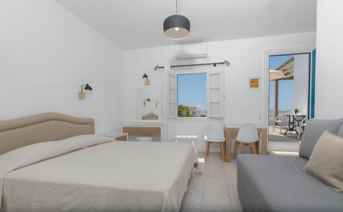 a white bedroom with a bed and a table and chairs at Esperides in Platis Gialos