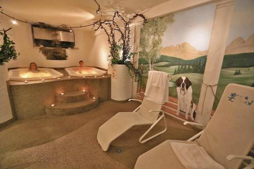 y baño con 2 lavabos, silla y bañera. en Hotel Vigo, en Vigo di Fassa
