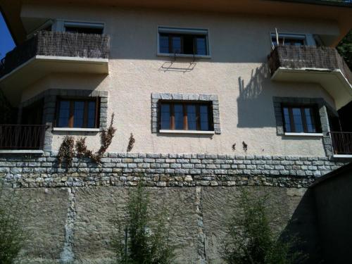 - un bâtiment avec des fenêtres au-dessus d'un mur en pierre dans l'établissement Appart-charme-Aix, à Aix-les-Bains